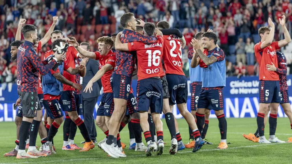CA Osasuna players in red and navy kits celebrate together on the pitch after a La Liga match.